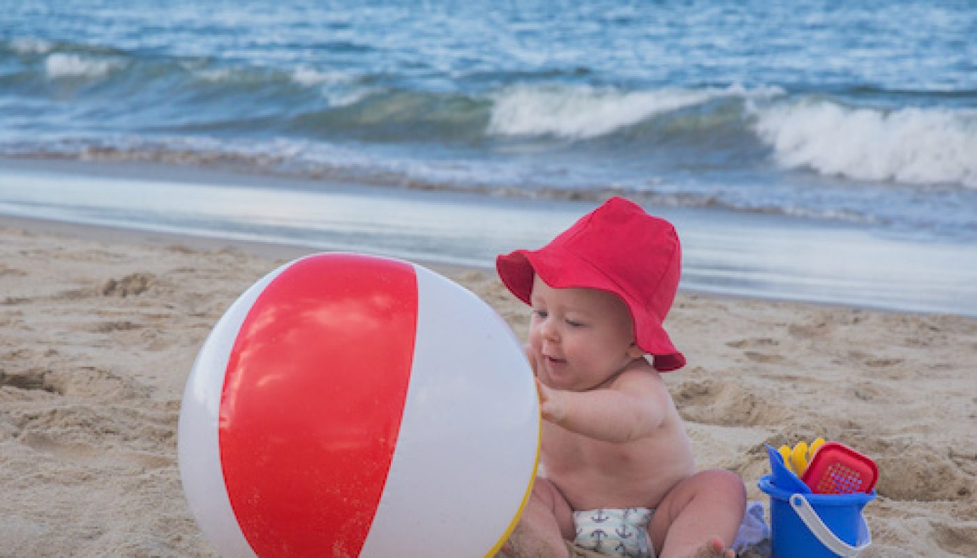 Cute Baby Playing with a Beach Ball in the sand